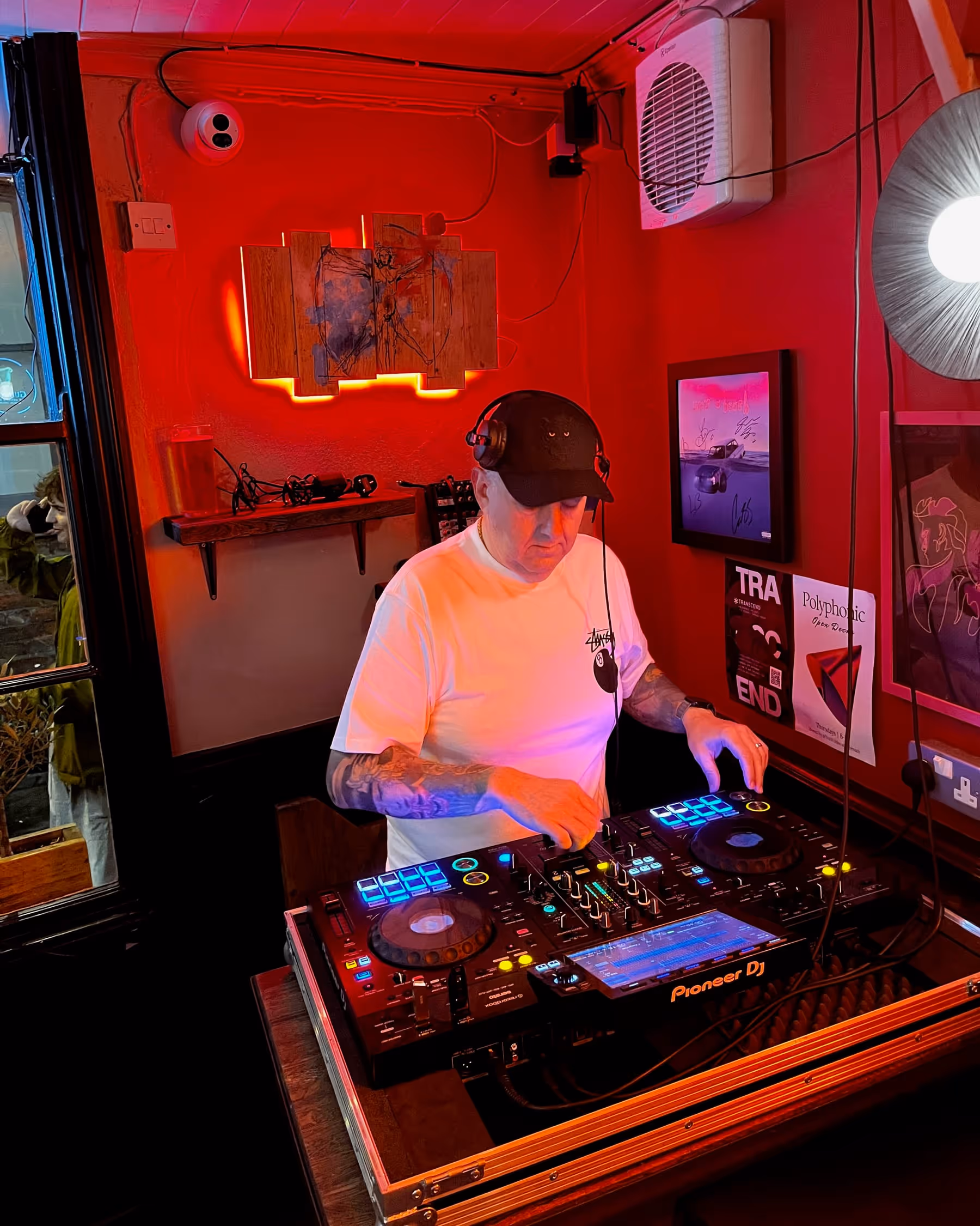 Tony T wearing headphones and mixing at Polymath under red lighting.