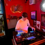 Tony T wearing headphones and mixing at Polymath under red lighting.